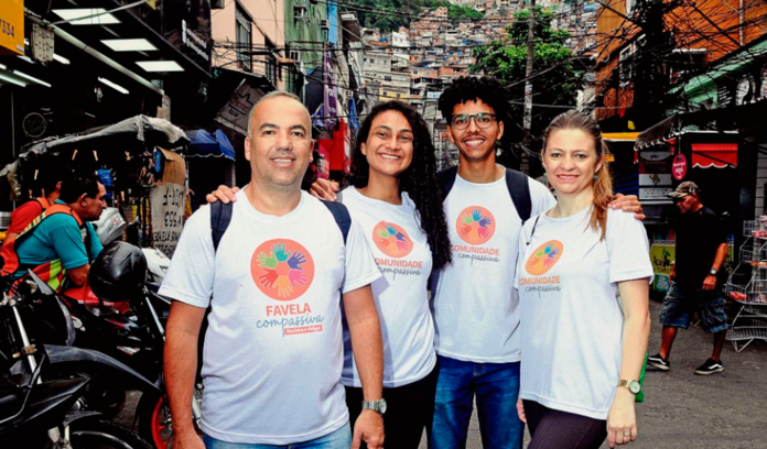 Integrantes do projeto Favela Compassiva com a comunidade que atendem ao fundo.