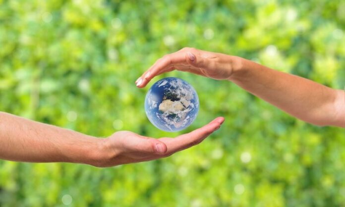 Mãos com o planeta Terra entre elas, indicando sustentabilidade.