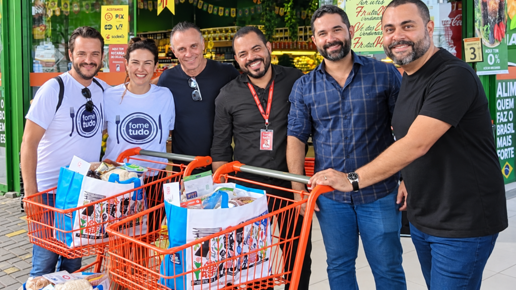 Grupo de voluntários e parceiros posa com carrinhos cheios de alimentos durante ação do Fome de Tudo no Recife