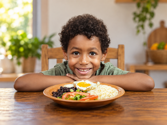 Criança sorridente diante de um prato de comida, em imagem ilustrativa sobre combate à fome e desperdício de alimentos