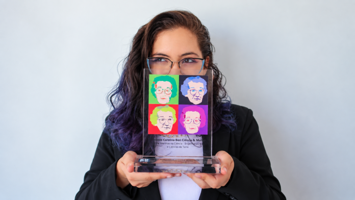 Narayane Ribeiro Medeiros segura troféu do Prêmio Carolina Bori Ciência & Mulher